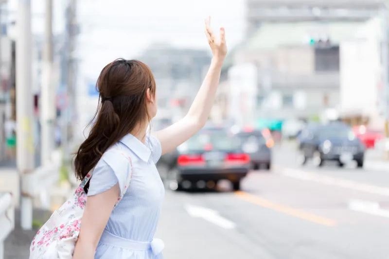 タクシーを捕まえるために手を挙げる女性